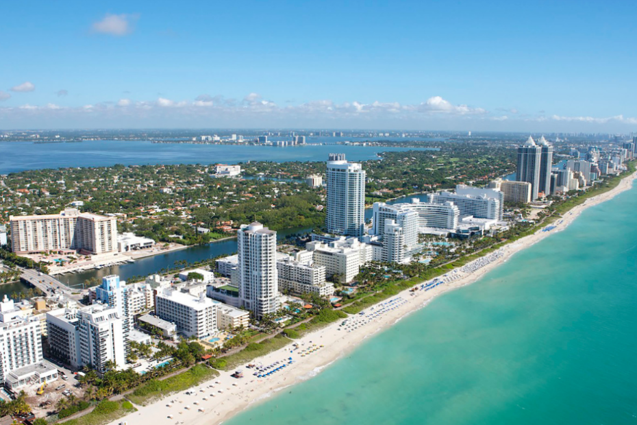 Vista aérea de hotéis luxuosos à beira-mar em Miami, destacando elegância e exclusividade.